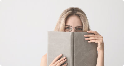 woman looking over book wearing glasses